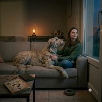 Mujer y su perro adoptado descansando tranquilamente en el sofá, capturando el vínculo emocional, la paciencia y la compañía incondicional que aporta la adopción de mascotas a un hogar.